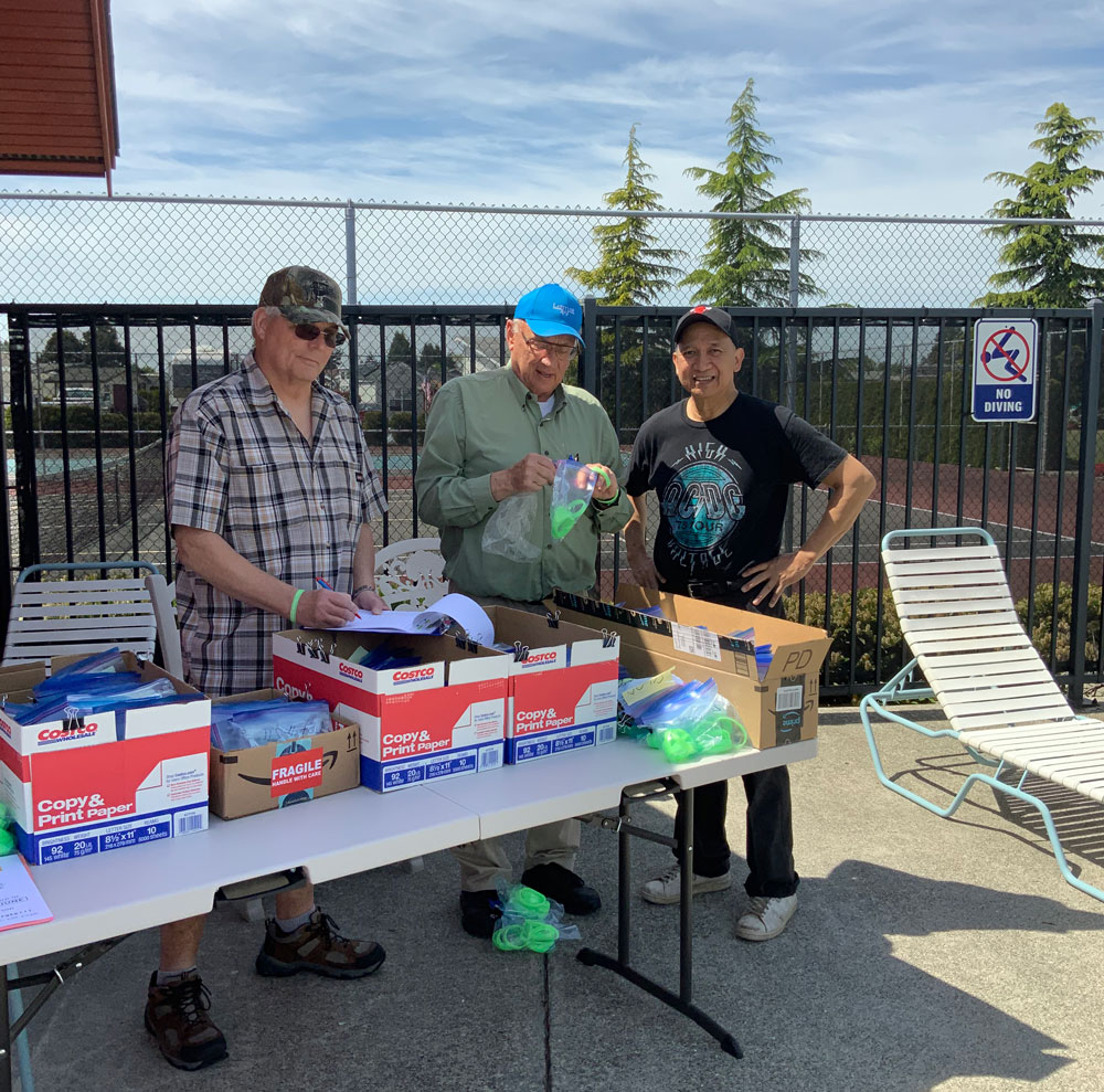 Volunteers distribute green bracelets to residents using the pool